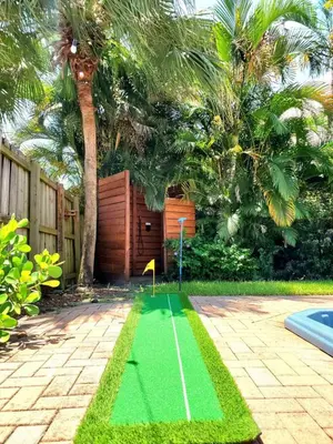 a green obstacle course in a backyard with a palm tree at Lux House Heated Spa & Free Boat Tour! in Fort Lauderdale