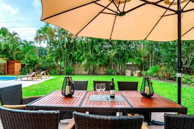 a wooden table with an umbrella and chairs at Lux House Heated Spa & Free Boat Tour! in Fort Lauderdale