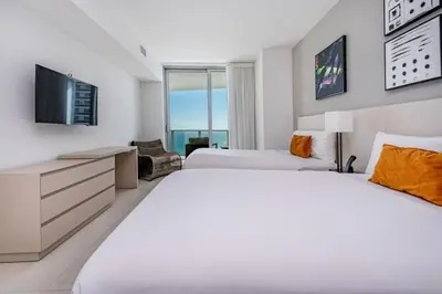 two beds in a room with a tv and a couch at Hyde Beach Luxury Condo-Resort apts in Hollywood Beach