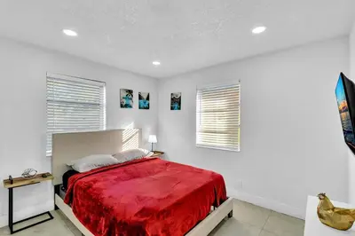a bedroom with a red bed and two windows at 2 Bdrm Modern House Mins From Beach & Casino Hb1 in Hallandale Beach