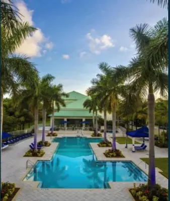 a pool with palm trees in front of a building at Doral 2-Story Villa 3 Bed 4 Bath at Provident Doral at The Blue Miami in Miami