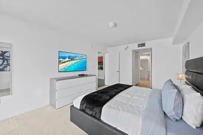 a white bedroom with a large bed and a flat screen tv at Private Unit Miami With Amenities And Parking in Miami