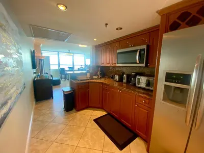 a kitchen with wooden cabinets and a white refrigerator at Castle Beach Resort Condo - Panoramic Large Penthouse or Deluxe 1 BR Direct Ocean View and beach access- Updated-Free parking- in Miami Beach