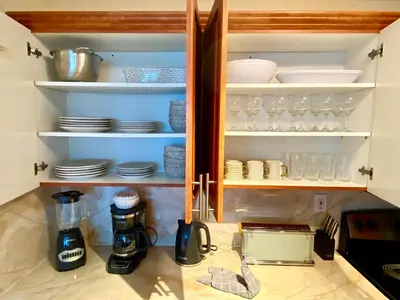 a kitchen cabinet with plates and glasses in it at Castle Beach Resort Condo - Panoramic Large Penthouse or Deluxe 1 BR Direct Ocean View and beach access- Updated-Free parking- in Miami Beach