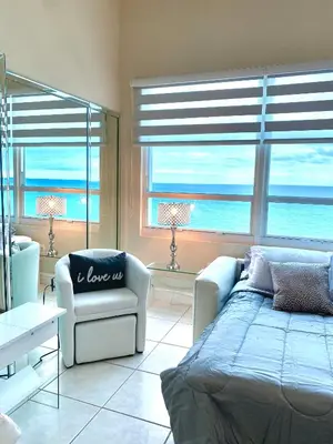 a bedroom with a bed and a couch and windows at Castle Beach Resort Condo - Panoramic Large Penthouse or Deluxe 1 BR Direct Ocean View and beach access- Updated-Free parking- in Miami Beach
