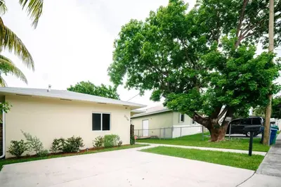 a house with a tree next to a driveway at New house on the block near Miami Airport. in Miami