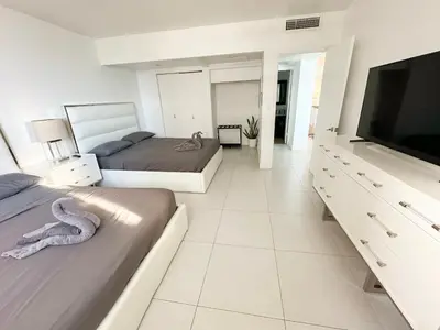 a bedroom with two beds and a flat screen tv at Amplio y moderno departamento con acceso directo a la playa in Hollywood