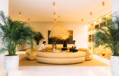 three people sitting on a couch in a room with palm trees at Flow Hotel Fort Lauderdale in Fort Lauderdale