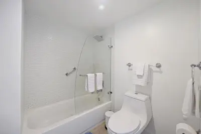a white bathroom with a toilet and a shower at Yacht Club at aventura Amazing Marina view parking included in Miami