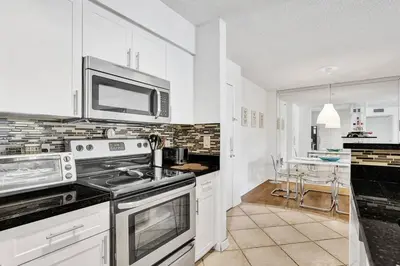 a kitchen with white cabinets and a stove top oven at Renovated cozy The yacht club at aventura Parking included in Miami