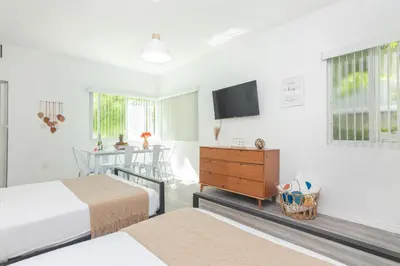a bedroom with two beds and a table with a television at West Deco in Miami Beach