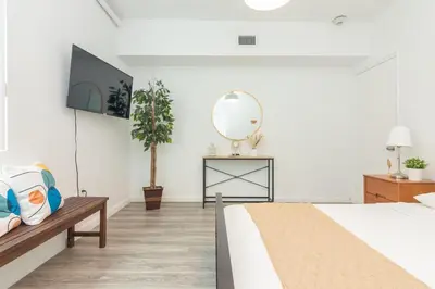 a white bedroom with a bed and a mirror at West Deco in Miami Beach