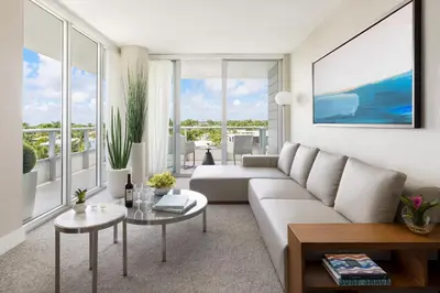a living room with a white couch and large windows at The Altair Bay Harbor Hotel in Miami Beach