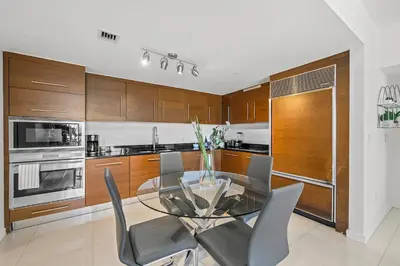 a kitchen with a glass table and wooden cabinets at *ICONIC W ICON CONDO/ POOL&WATERVIEWS*FREESPA* in Miami