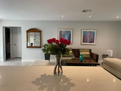 a living room with a vase of red roses on a table at SuperVilla - 3BR/2BA - Pool - Walk to beach in Hollywood