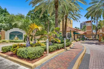 a walkway in front of a building with palm trees at Yacht Club Newly renovated parking included in Aventura