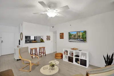a living room with a ceiling fan and chairs at Yacht Club Newly renovated parking included in Aventura