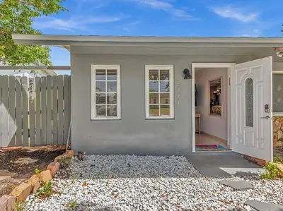 a gray house with a white door and a fence at SuperVilla - Lakefront - Sunsets, Kayaks, Grill in Fort Lauderdale