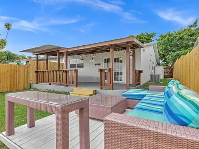 a backyard with a wooden deck with tables and a pavilion at SuperVilla - Lakefront - Sunsets, Kayaks, Grill in Fort Lauderdale