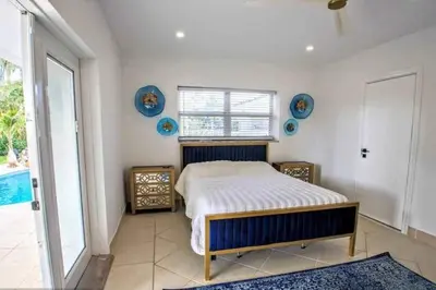 a bedroom with a bed and a large window at SWAYING PALM BEACH HOUSE Walk to Beach , Marina, Port, las Olas in Fort Lauderdale