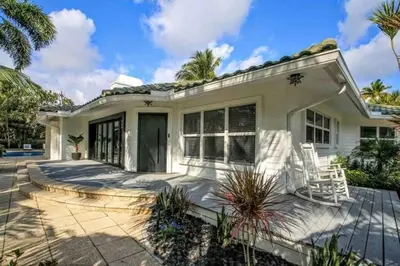 a white house with a patio and palm trees at SWAYING PALM BEACH HOUSE Walk to Beach , Marina, Port, las Olas in Fort Lauderdale
