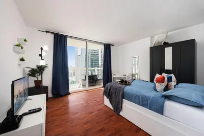 a bedroom with a bed with blue sheets and a television at Two Bedroom Oceanview Apartment in Brickell in Miami