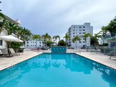 a pool with palm trees and buildings in the background at Tranquilo in Fort Lauderdale