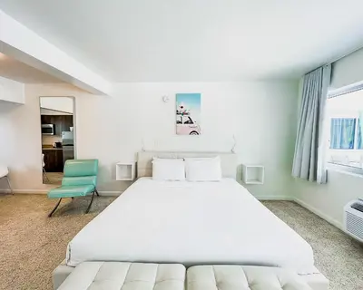 a bedroom with a large white bed and a blue chair at Tranquilo in Fort Lauderdale