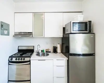 a kitchen with white cabinets and a stainless steel refrigerator at Tranquilo in Fort Lauderdale
