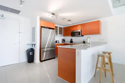 a kitchen with wooden cabinets and a stainless steel refrigerator at Relax Family Midtown - free parking & Great pool in Miami