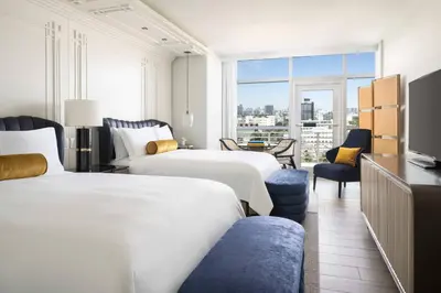 a hotel room with two beds and a tv at The Ritz-Carlton, South Beach in Miami Beach