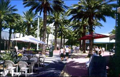 a group of people walking down a sidewalk with palm trees at Island House South Beach in Miami Beach