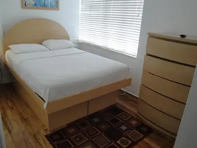 a bed in a bedroom with a wooden headboard and a window at Island House South Beach in Miami Beach
