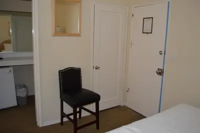 a chair in a room with a bed and a mirror at Island House South Beach in Miami Beach