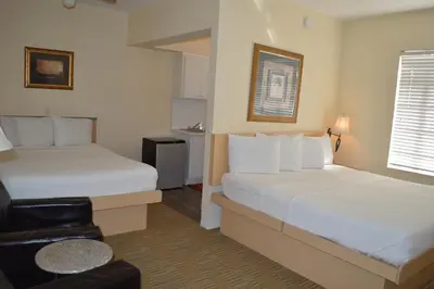 a hotel room with two beds and a chair at Island House South Beach in Miami Beach