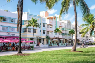 a street with palm trees in front of a building at Roami at The Carmela in Miami Beach