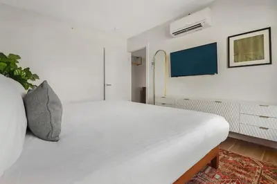 a bedroom with a white bed with a tv on the wall at Roami at The Carmela in Miami Beach