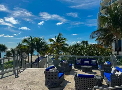 a patio with chairs and palm trees on the beach at MVR Apartments at Marenas in Miami Beach