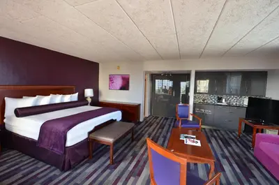 a hotel room with a large bed and a table at Sea Club Ocean Resort in Fort Lauderdale
