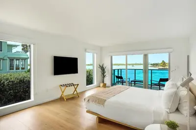 a white bedroom with a large bed and a balcony at Beach Haus Bal Harbour in Miami Beach