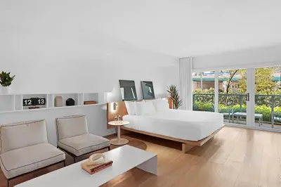 a white bedroom with a bed and a couch and chairs at Beach Haus Bal Harbour in Miami Beach