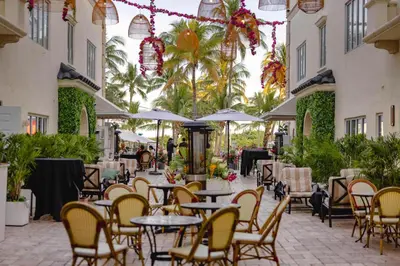 a patio with tables and chairs and palm trees at Hotel Ocean in Miami Beach