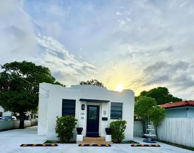 a white house with the sun setting behind it at Cozy Private House near Miami Airport - Free parking - 01 in Miami