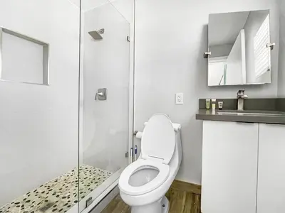 a bathroom with a toilet and a glass shower at Neptune Oceanfront Rentals in Hollywood