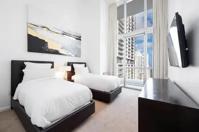 a bedroom with two beds and a tv and a window at ICONIC LUXURIOUS HIGH CEILINGS UNIT BRICKELL w in Miami
