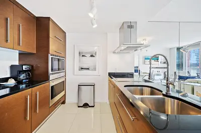 a kitchen with wooden cabinets and a stainless steel sink at Majestic High Rise Unit with Ocean view in Miami