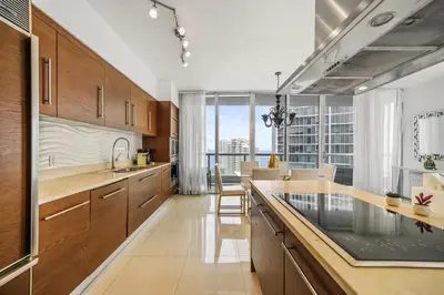 a kitchen with wooden cabinets and a large window at Breathtaking Ocean View Unit Icon Brickell W in Miami