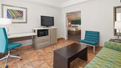 a hotel room with a couch and a desk and a tv at Best Western Plus Oceanside Inn in Fort Lauderdale