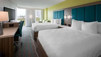 a hotel room with two beds and a television at Best Western Plus Oceanside Inn in Fort Lauderdale