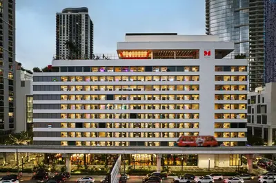 a large white building with cars parked in a parking lot at citizenM Miami World Center in Miami